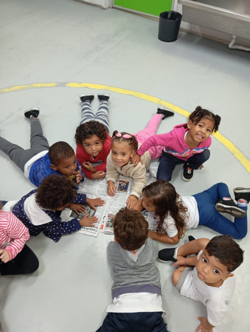 Em um círculo de descobertas, as crianças da EI 23 exploraram o jornal com encantamento e curiosidade.<br />
Deitadas lado a lado, olharam atentamente cada página, cada imagem, cada história — aprendendo que o mundo cabe dentro de um papel… e dentro da imaginação de quem lê.