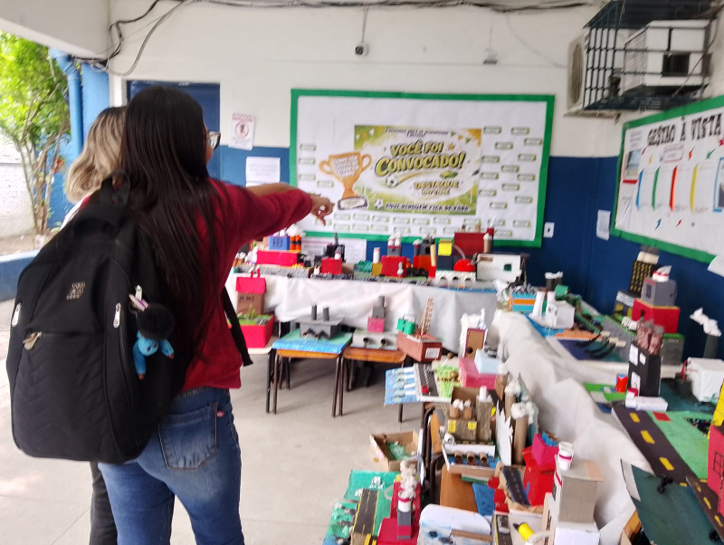 Alunas visitando a exposição de maquetes sobre Revolução Industrial do 8º ano do Ensino Fundamental II.