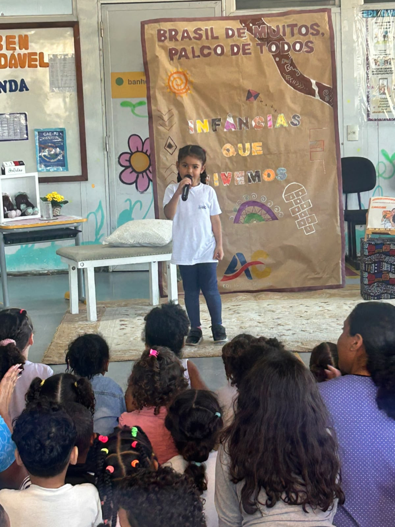 Cada verso declamado tornou-se uma oportunidade de protagonismo. Cada voz infantil revelou que as crianças têm muito a dizer, sentir, imaginar e ensinar. Na foto, Eloah também registra esse momento de participação e protagonismo, compartilhando a beleza de sua expressão e vivência.