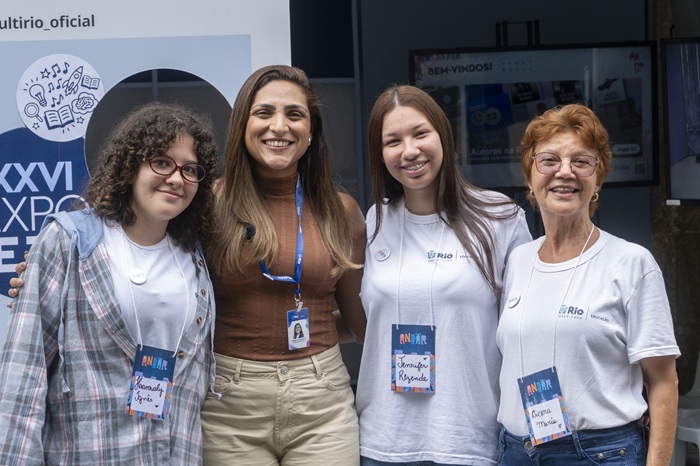 A presidente da MultiRio, Angelina Moreira, posa para foto ao lado das estudantes Hannaly Ignês, Jennifer Rezende e Cícera Maria durante a XXVI ExpoEJA. As quatro aparecem em frente ao estande da MultiRio.